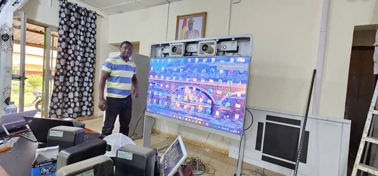 Écran interactif installé dans une salle, avec un technicien GENESIS-GUINÉE à proximité