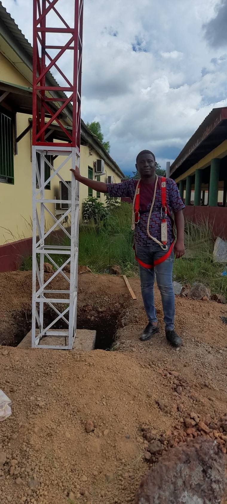 Technicien GENESIS-GUINÉE en harnais de sécurité près d'un pylône télécom en cours de montage